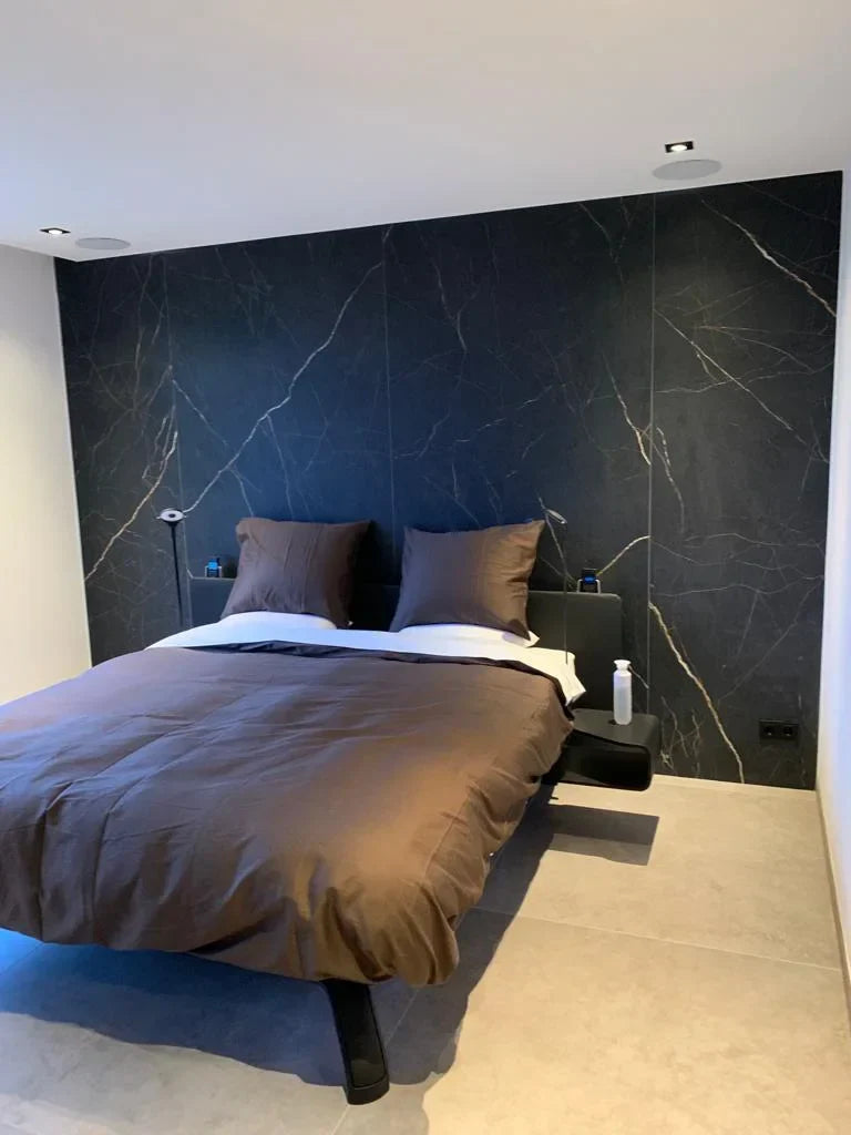 Luxe slaapkamer met marmerlook wandtegels en bruin bedlinnen